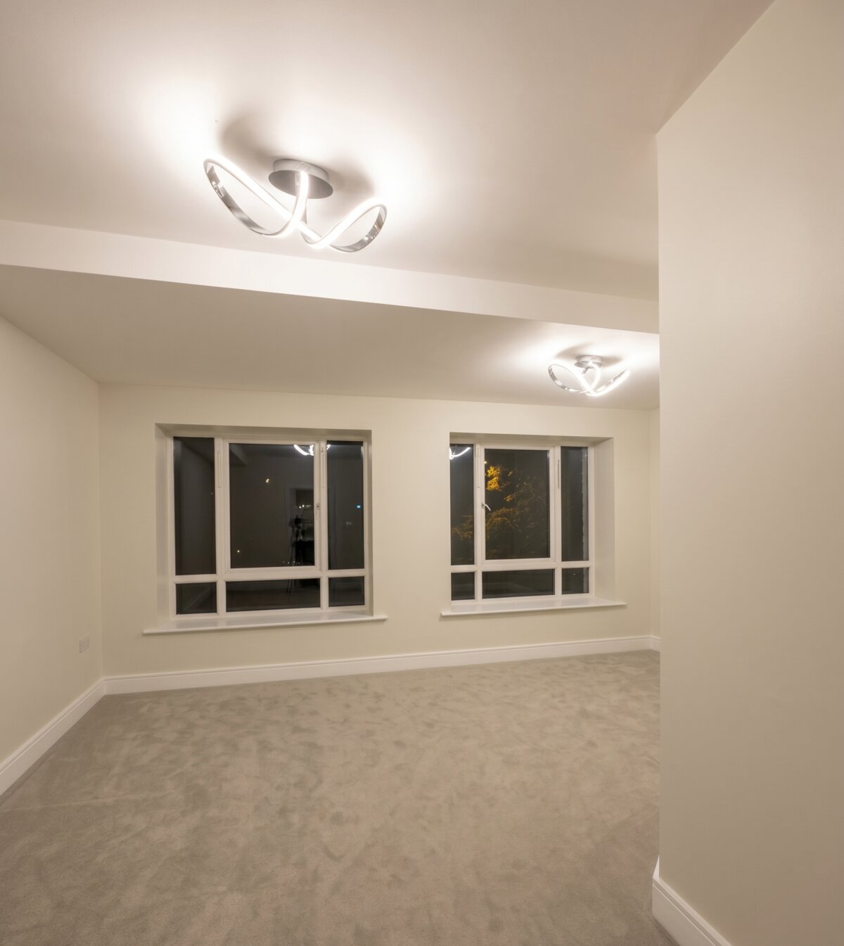 Painted Dublin bedroom with two windows, modern ceiling lights, and soft neutral walls